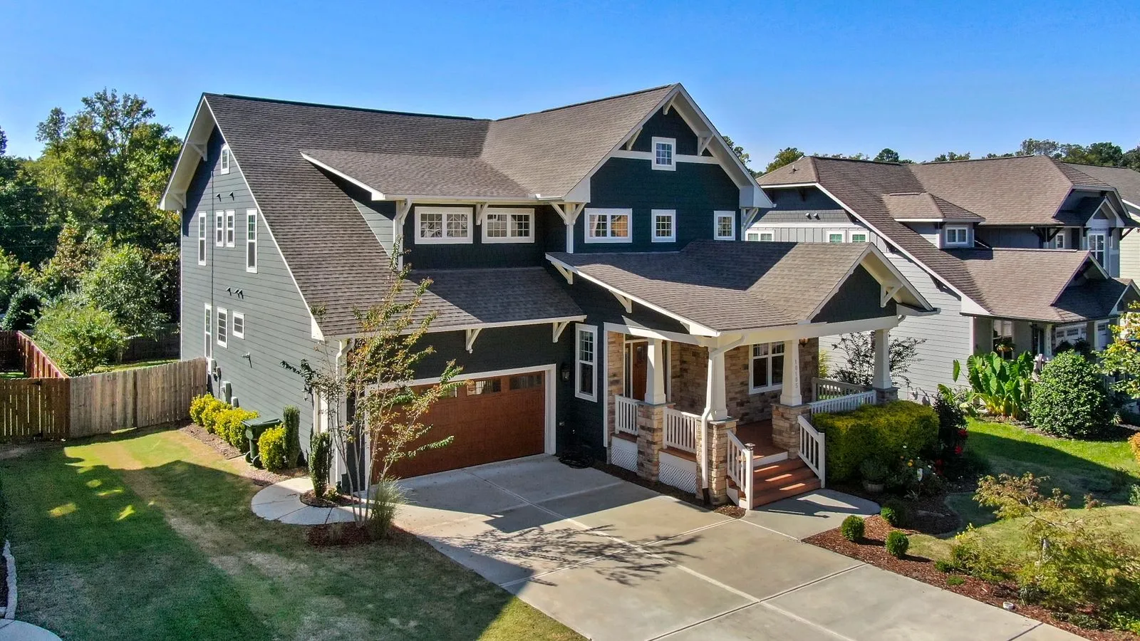 A spacious grey craftsman-style home with a covered porch and landscaped yard.
