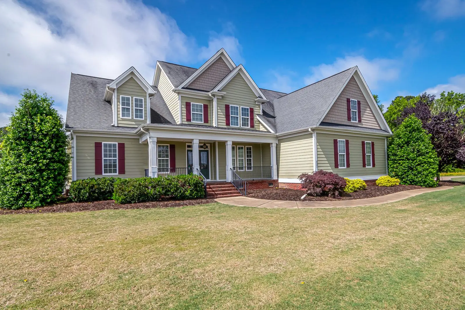 A well-kept detached home with a covered front porch and a broad lawn.